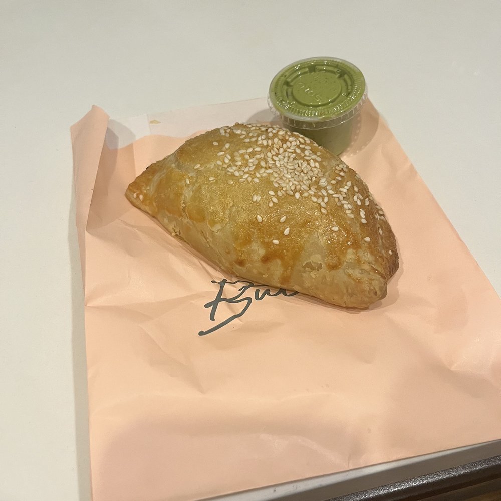 a pastry on a piece of paper with a cup of green tea a pastry on a piece of paper with a cup of green tea