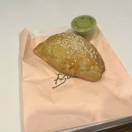 a pastry on a piece of paper with a cup of green tea a pastry on a piece of paper with a cup of green tea