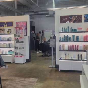 Aveda Institute - Orlando - Product shelves w/ a peek into the salon section - Cosmetology Schools Near Me - Winter Park, Florida