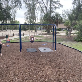 Christopher And Jarrod Ditmar's Playground - Swings, and in the distance, the restrooms! - Playgrounds Near Me - Sarasota, Florida Christopher And Jarrod Ditmar's Playground - Swings, and in the distance, the restrooms! - Playgrounds Near Me - Sarasota, Florida