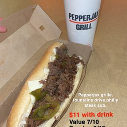 Philly steak - A Philly steak sub with beef, green peppers, and cheese in a cardboard box, accompanied by a large drink in a PepperJax Grill cup.