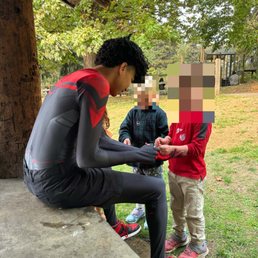 Spider-man (Miles Morales) putting temporary tattoos on two little kids