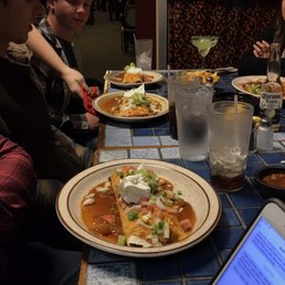 a group of people sitting at a table with plates of food