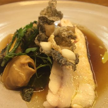 Common Lot - Branzino poached in olive oil with mussels and clams, collard greens and sea beans in a roasted onion consommé, crispy branzino skin, sauce - New American Near Me - Millburn, New Jersey Common Lot - Branzino poached in olive oil with mussels and clams, collard greens and sea beans in a roasted onion consommé, crispy branzino skin, sauce - New American Near Me - Millburn, New Jersey
