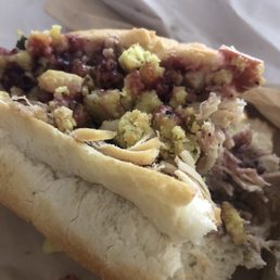 The Bobbie - A sandwich with sliced meat, cheese, and toppings inside a bread roll, partially eaten, on a paper surface.