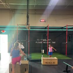 Davidson Strength Fitness - Woman coach in purple shirt coaching kids through a group workout with boxes.