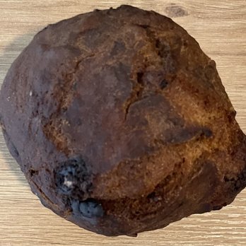 Gregorys Coffee - Banana chocolate chip muffin - A rusted, irregularly shaped object with a rough, textured surface and a dark brown coloration. The object appears to be a small, weathered item, possibly a piece of metal or mineral, resting on a wooden surface. Its shape is uneven, with some protrusions and a somewhat rounded form. - Coffee & Tea Near Me - Washington, DC, District of Columbia