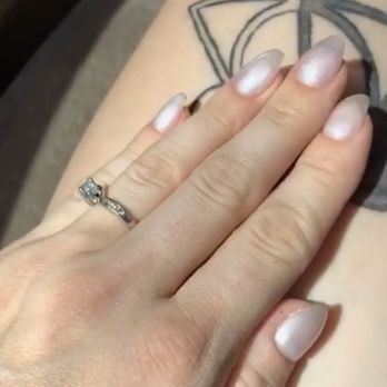 Refresh Salon - A close-up of a hand with a wedding ring placed on a tattooed area of skin, showing well-manicured nails. - Hair Salons Near Me - Phoenix, Arizona