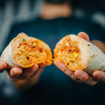 Bubbakoo's Burritos - a person holding a burrito - Mexican Near Me - Orlando, Florida