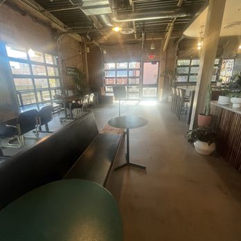 CoffeeDrunk - A cafe interior featuring large windows, seating areas with chairs and tables, and decorative plants, with an industrial ceiling design. - Coffee & Tea Near Me - Phoenix, Arizona