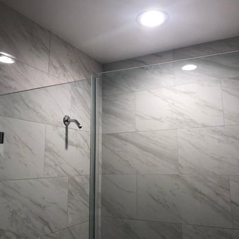 Green American Builders - a shower with a glass door - Flooring Near Me