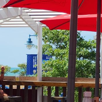 Willie's Beach Bar - a man sitting at a table with red umbrellas - Bars Near Me - Grand Bend, Ontario Willie's Beach Bar - a man sitting at a table with red umbrellas - Bars Near Me - Grand Bend, Ontario