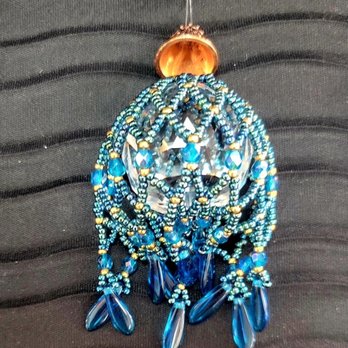 Beaded Iris - A beaded jewelry ornament featuring intricate blue beads, gold accents, and dangling blue teardrop-shaped beads, set against a black textured background. - Arts & Crafts Near Me - Albuquerque, New Mexico