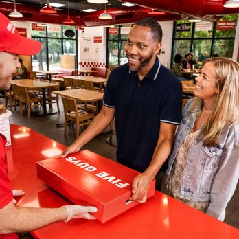 Five Guys - A couple collect their Five Guys catering box from a Five Guys employee at a Five Guys restaurant. - Burgers Near Me - Wausau, Wisconsin
