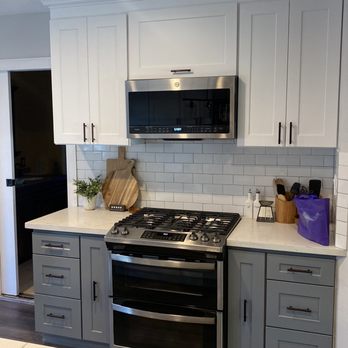 Avelar Remodeling - a kitchen with white cabinets and stainless steel appliances - Flooring Near Me