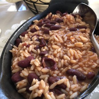 Solar Do Minho - Rice and beans - A serving of rice and beans in a black skillet, with a metal spoon resting inside, on a table with a basket and napkin in the background. - Portuguese Near Me - Belleville, New Jersey