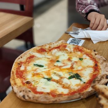 Settebello - a person cutting a pizza - Pizza Near Me - Saint Paul, Minnesota Settebello - a person cutting a pizza - Pizza Near Me - Saint Paul, Minnesota