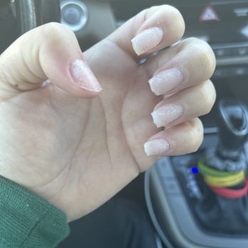 De Paris Nails - A person's hand with long, unpolished nails is visible inside a vehicle, with the car's dashboard and gear shift in the background. - Nail Salons Near Me - Centerville, Massachusetts