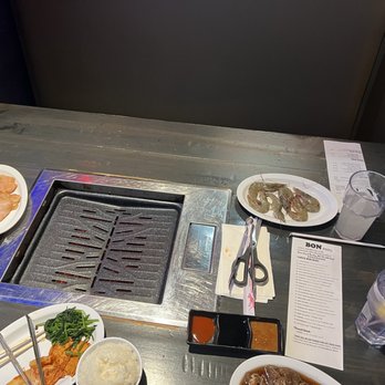 BON Kbbq - This is the seating, gas grill and several plates. The meat is brought out to you as you order. Limits cross contamination. - Korean Near Me - Houston, Texas BON Kbbq - This is the seating, gas grill and several plates. The meat is brought out to you as you order. Limits cross contamination. - Korean Near Me - Houston, Texas