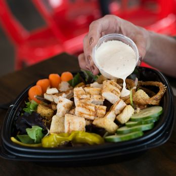 Slim Chickens - a person pouring dressing over a salad - Southern Near Me - Westfield, Indiana Slim Chickens - a person pouring dressing over a salad - Southern Near Me - Westfield, Indiana