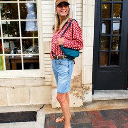 Fashion-forward women's clothing and accessories displayed in a lifestyle setting, featuring casual wear, denim shorts, handb...
