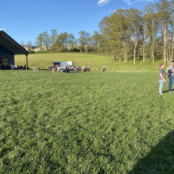 Eastern Divide - Grassy outdoor area - A group of people is gathered outdoors on a grassy area near a building and trees, with a clear blue sky overhead. - Brewpubs Near Me - Blacksburg, Virginia
