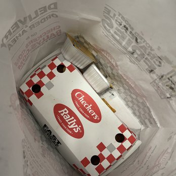 Checkers - a package of cigarettes in a plastic bag - A paper bag holds a Checkers/Rally's burger box and small condiment containers, likely from a fast-food restaurant. - Fast Food Near Me - Elgin, Illinois