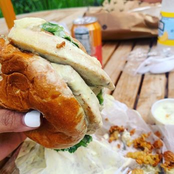 Sandy's Fish and Chips - a hand holding a sandwich - Seafood Near Me - Vineyard Haven, Massachusetts Sandy's Fish and Chips - a hand holding a sandwich - Seafood Near Me - Vineyard Haven, Massachusetts