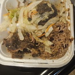 Half eaten jerk chicken, rice and peas and cabbage