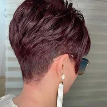 Hey Red! - A woman with a short, layered haircut dyed in dark red, wearing glasses and a long, beaded earring. - Hair Salons Near Me - Laurel, Maryland