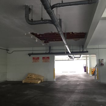 Beach Front Property Management - Hole in the ceiling of the carport with a large pile of insulation - the area was left in this condition for weeks - Property Management Near Me - Long Beach, California