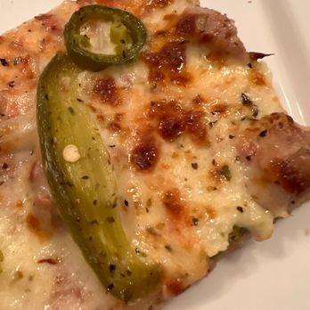 Santis Pizza - Sausage, jalapeño and onions - A pizza slice with melted cheese, jalapeño slices, and herbs on a white plate. - Pizza Near Me - Aurora, Illinois