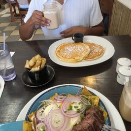 Buttermilk pancakes. Tomatillo sauce chilaquiles with steak. Side of potatoes in a cup. Horchata latte and caramel latte.