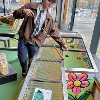 Flatstick Pub - South Lake Union - Our friend Yari figuring out his putting strategy. - Mini Golf Near Me - Seattle, Washington Flatstick Pub - South Lake Union - Our friend Yari figuring out his putting strategy. - Mini Golf Near Me - Seattle, Washington