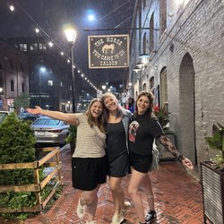 Baltimore Ghost Tours - Three girls excitedly posing under the sign for "The Horse You Came in On Saloon"