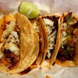 three tacos with a lime wedge three tacos with a lime wedge