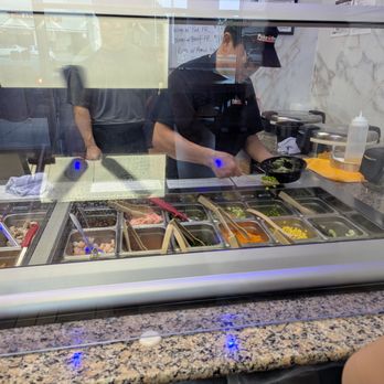 Poke Dream - Inside. Poke bar. This employee is preparing my wife's custom bowl. Our bowls were delicious. - Hawaiian Near Me - High Point, North Carolina