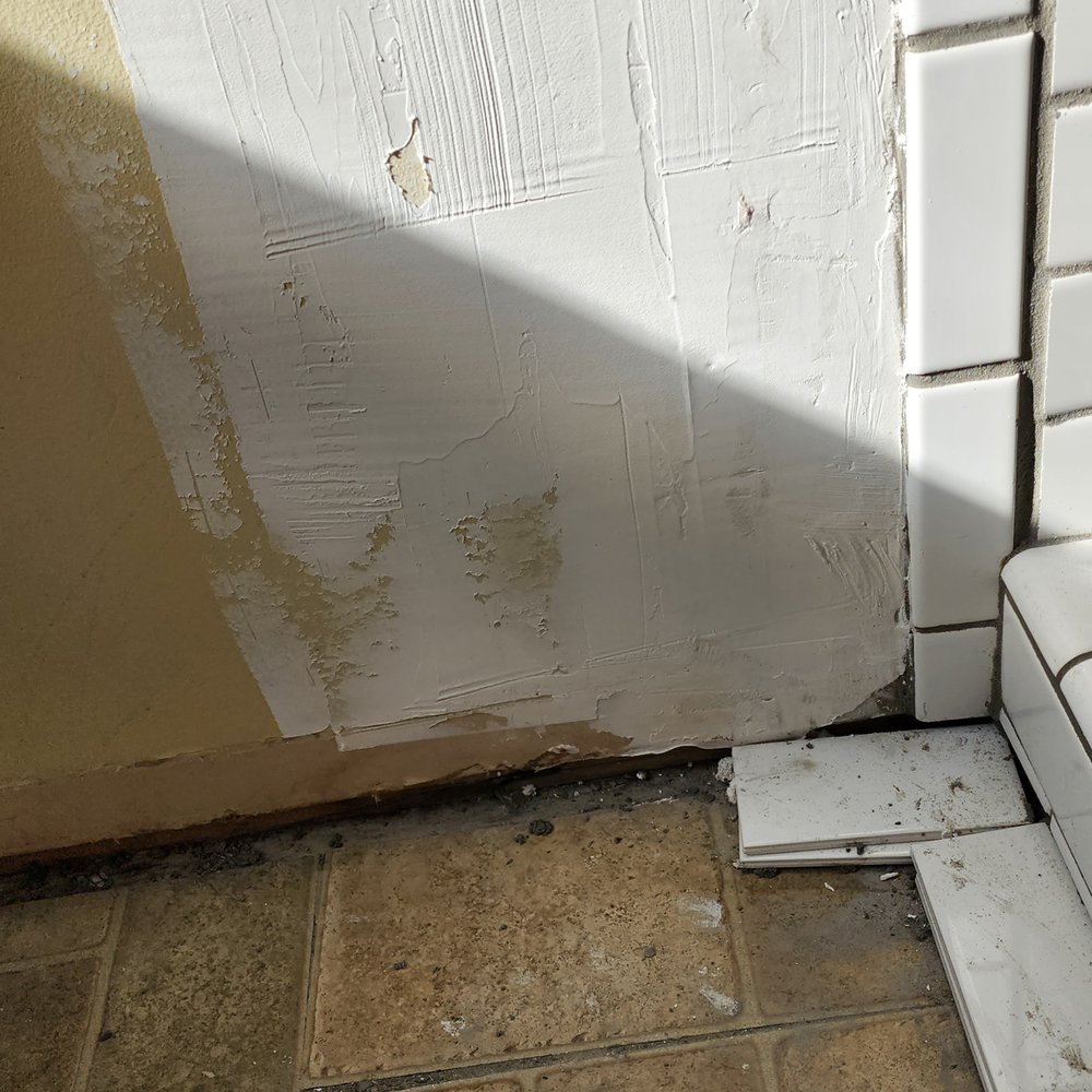 Garber Construction - missing baseboard and spackle on wall. extra tiles holding up tiles on curb of shower bc grout was still wet - General Contractors Near Me - Winston-Salem, North Carolina