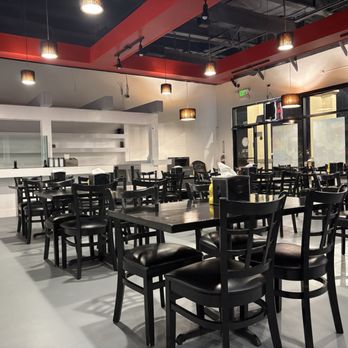 Ely's - Interior of restaurant. A bunch of black tables and chairs. White bar in back. Orange beams make up the ceiling. - Mexican Near Me - Spring Valley, Nevada