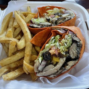 Jerky Jerk - Jerky Wrap - Jerk chicken wraps filled with lettuce, vegetables, and black beans, accompanied by French fries in a foam takeout box. - Caribbean Near Me - Rolling Meadows, Illinois