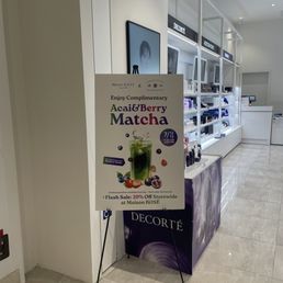 Amazing place, the staff is friendly and a very well organized event. My girlfriend loves the products the most! - A freestanding promotional sign in a retail store advertises a berry matcha drink available on July 12 and 13 from 11:00 AM to 2:00 PM, with a 20% storewide discount. The sign features an image of a green matcha drink with berries and mentions a limited quantity offer. The store interior includes shelves with beauty products, digital screens, and a clean, modern design.