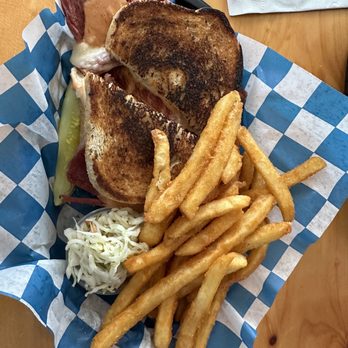 Frog Rock Tavern - Rueben - A meal featuring a toasted sandwich with grilled bread, served with French fries and a small portion of coleslaw, on a checkered paper liner. - New American Near Me - Meredith, New Hampshire
