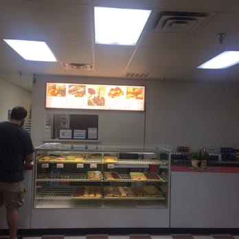 Donut Palace - a man standing in front of a display of donuts - Donuts Near Me - Arlington, Texas