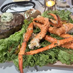 crab legs, steak, and lettuce on a cutting board