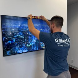 Grindlex Home Services - Professional technician using a leveling tool to ensure the wall-mounted TV is perfectly straight.