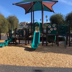 Jackson Park - Cute enclosed playground with swings and surrounding grass and picnic tables