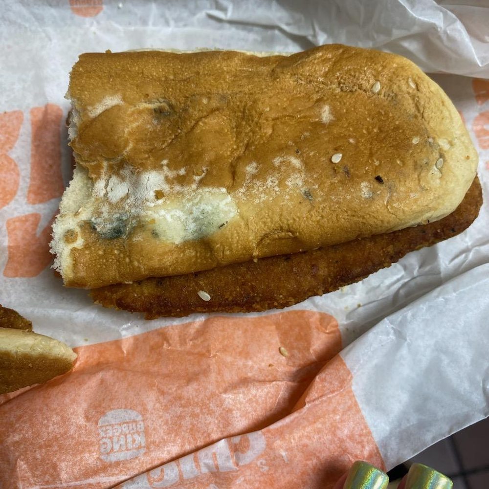 a hand holding a half eaten sandwich