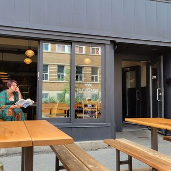 Isle de Garde - a woman sitting at a table outside of a restaurant - Brasseries Near Me - Montreal, Quebec