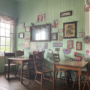 Shorty's Eatery - Interior - A dining area with wooden tables and chairs, green paneled walls, and a window with floral curtains, decorated with framed pictures and signs. - Sandwiches Near Me - Shasta, California