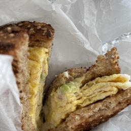 Egg, cheese, avocado breakfast sandwich on wheat toast.